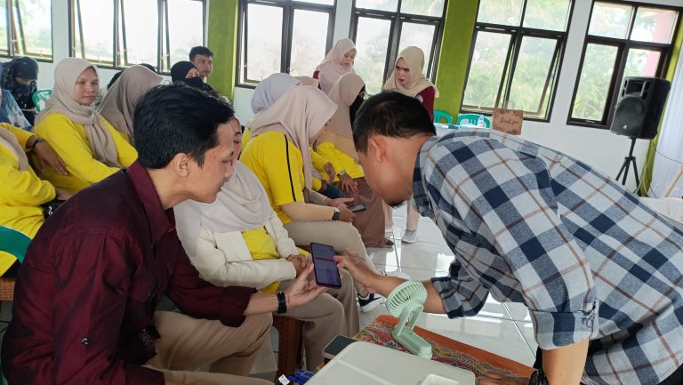 Narasumber Sekaligus Dosen Politeknik Triguna Tasikmalaya, Didin Syahidin memberikan panduan teknis secara langsung kepada pelaku UMKM Cisayong dalam mengoperasikan fitur live commerce melalui gawai pintar, Kamis (25/12/2025). Pelatihan ini menargetkan penguasaan fitur "Keranjang Kuning" untuk persiapan pasar Ramadan.