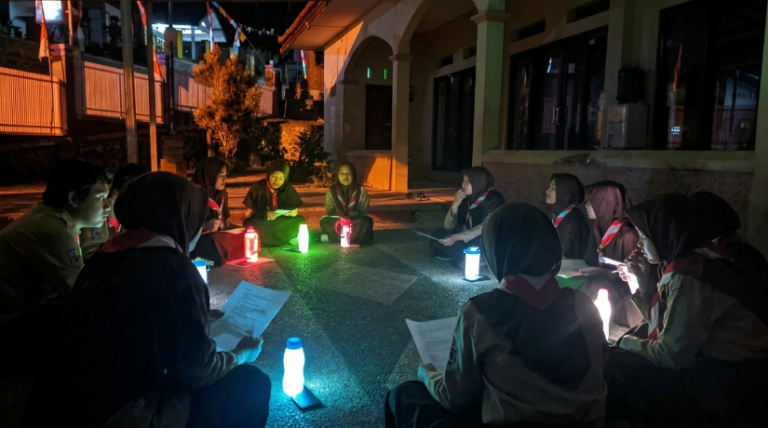 Peserta renungan malam menjelang Hari Pramuka ke-65 duduk melingkar mengelilingi pendar cahaya dari telepon genggam yang menembus tumbler di Pesantren Pramuka Khalifa, Tasikmalaya, Kamis (13/8/2026).
